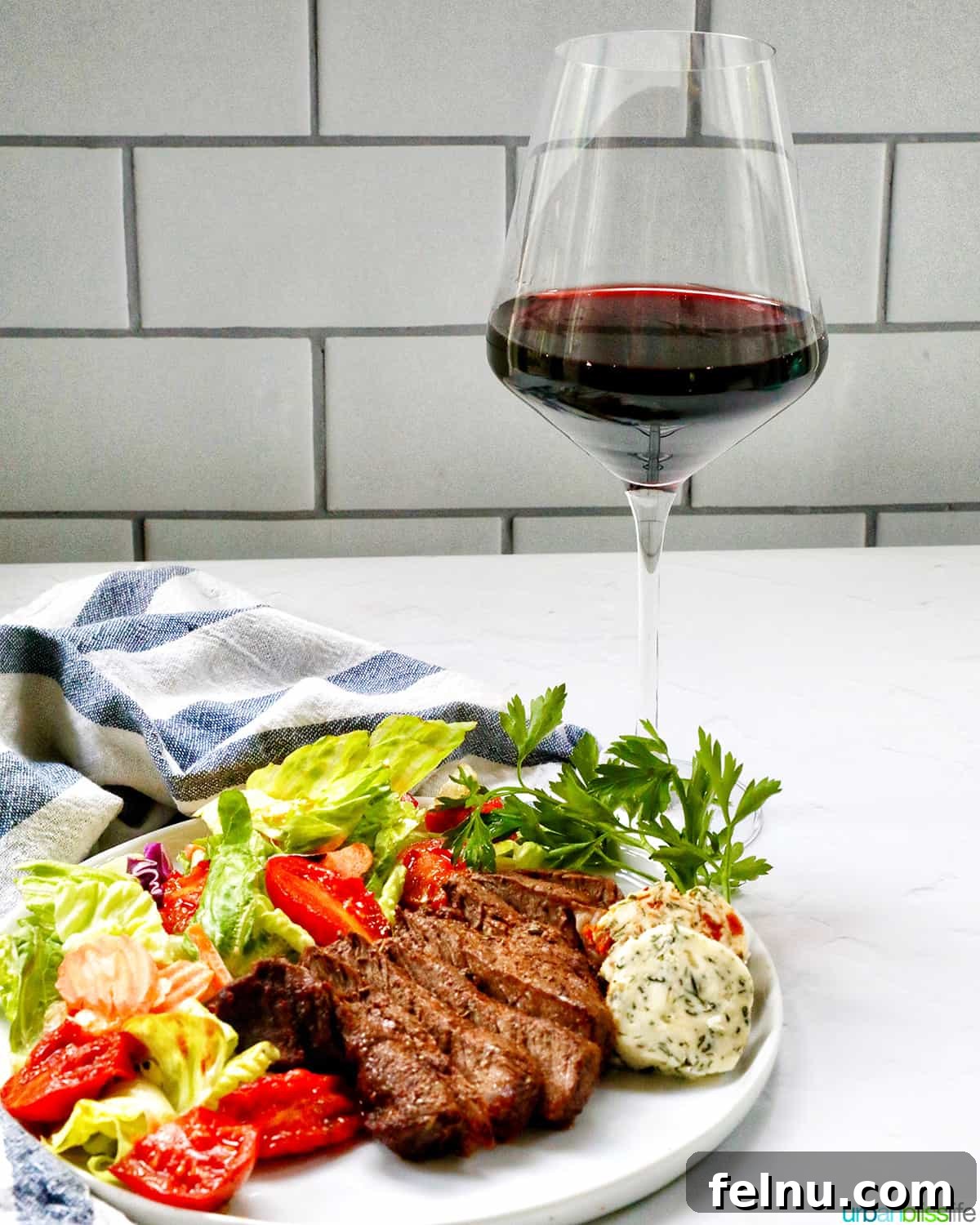 Air Fryer Filet Mignon Perfection 13 a glass of red wine paired with a plate of sliced filet mignon and a fresh green salad.