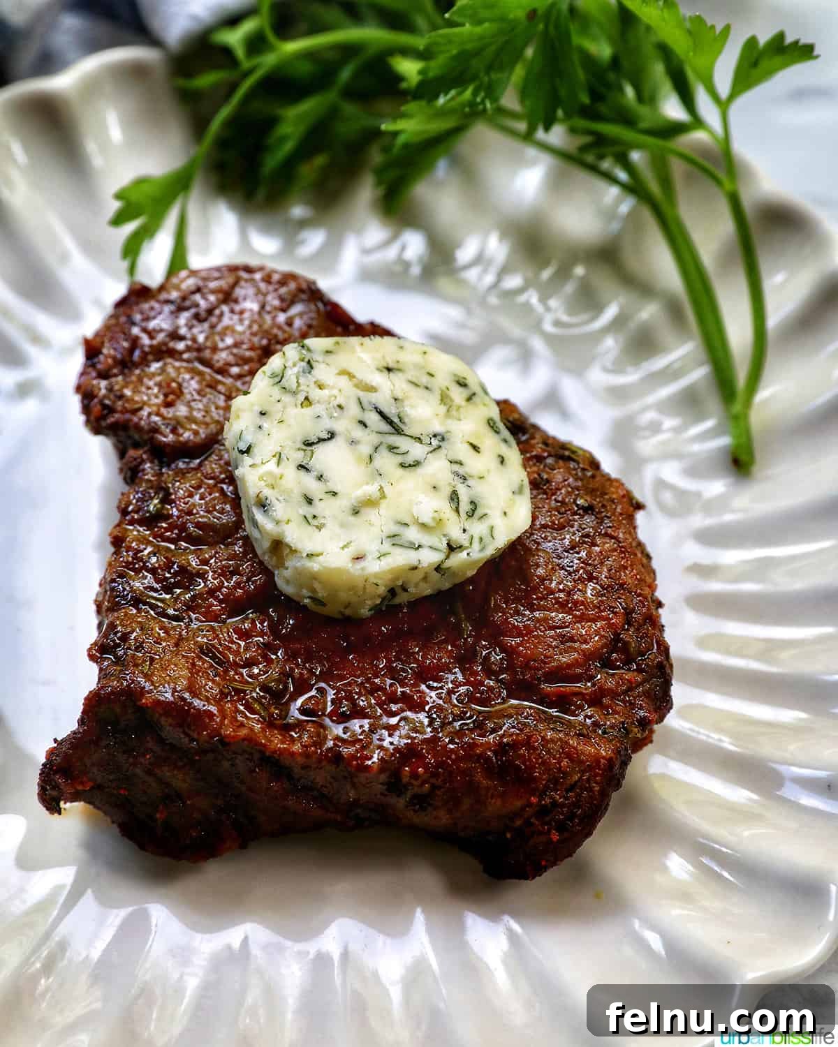 Air Fryer Filet Mignon Perfection 3 a perfectly cooked filet mignon steak on a plate with herb compote butter melting on top.