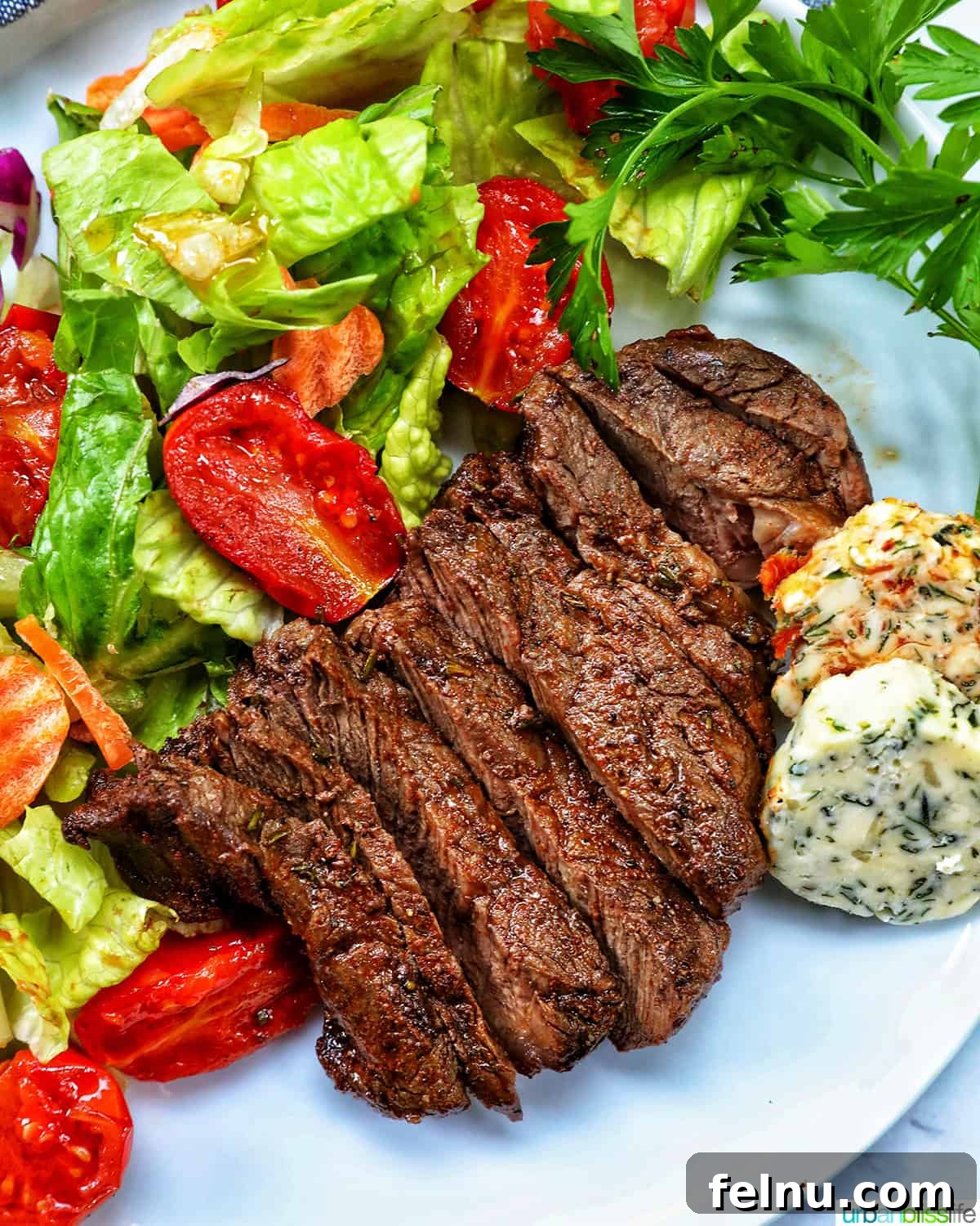 Air Fryer Filet Mignon Perfection 4 sliced air fryer filet mignon steaks arranged artfully with a side salad on a serving platter.
