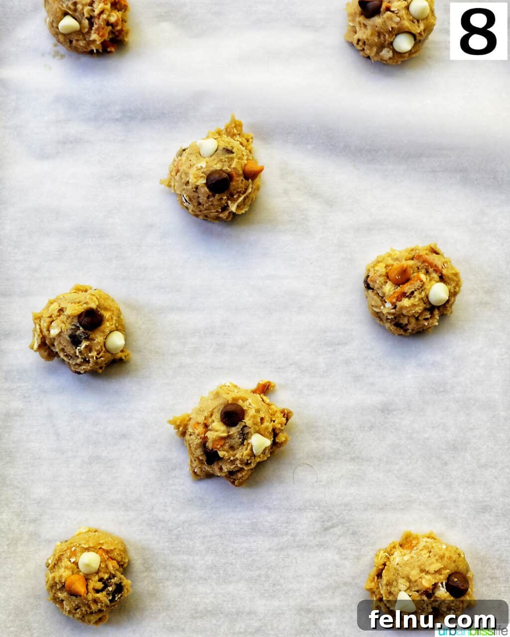 cookie dough balls on parchment paper on a baking sheet.