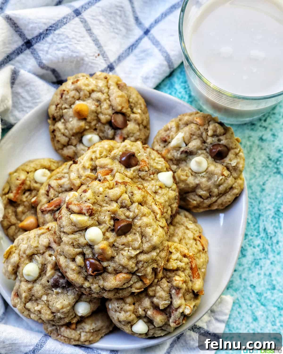 chocolate chip pretzel cookies stacked on a plate with a glass of milk.