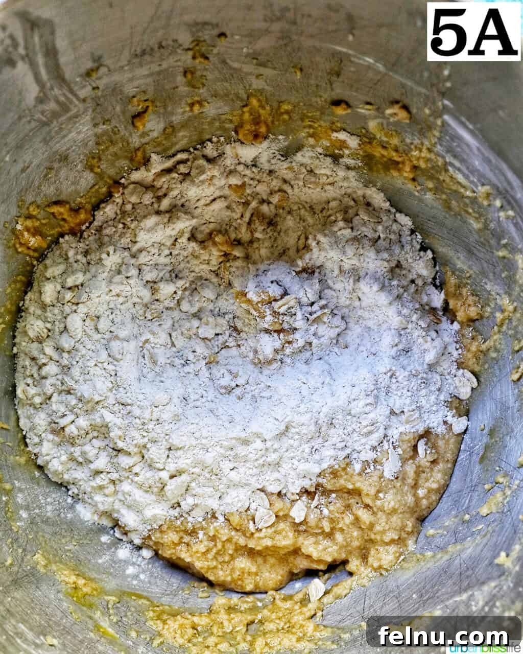adding dry ingredients to wet ingredients in a stand mixer bowl.