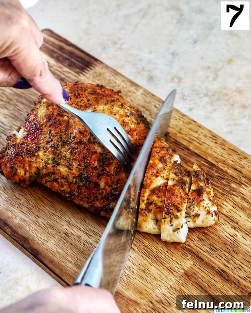 Perfect Air Fryer Turkey Tenderloin 12 A fork and knife expertly slicing into a perfectly cooked turkey tenderloin on a wooden cutting board, revealing its juicy interior.