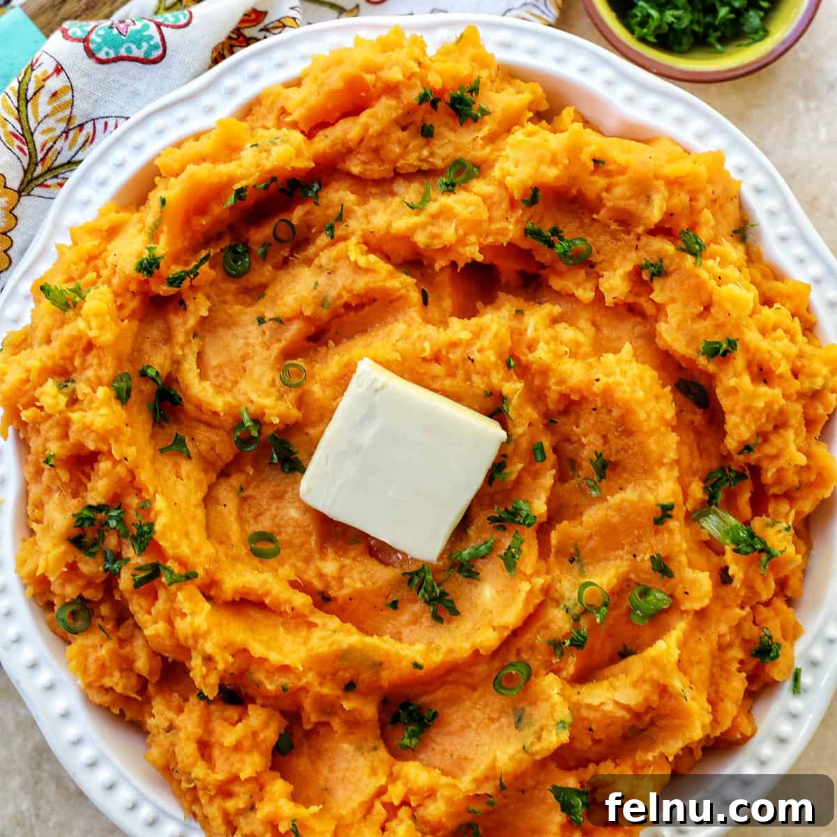 Silky Sweet Potato Puree 2 bowl of whipped sweet potatoes and a pat of butter with fresh herbs.