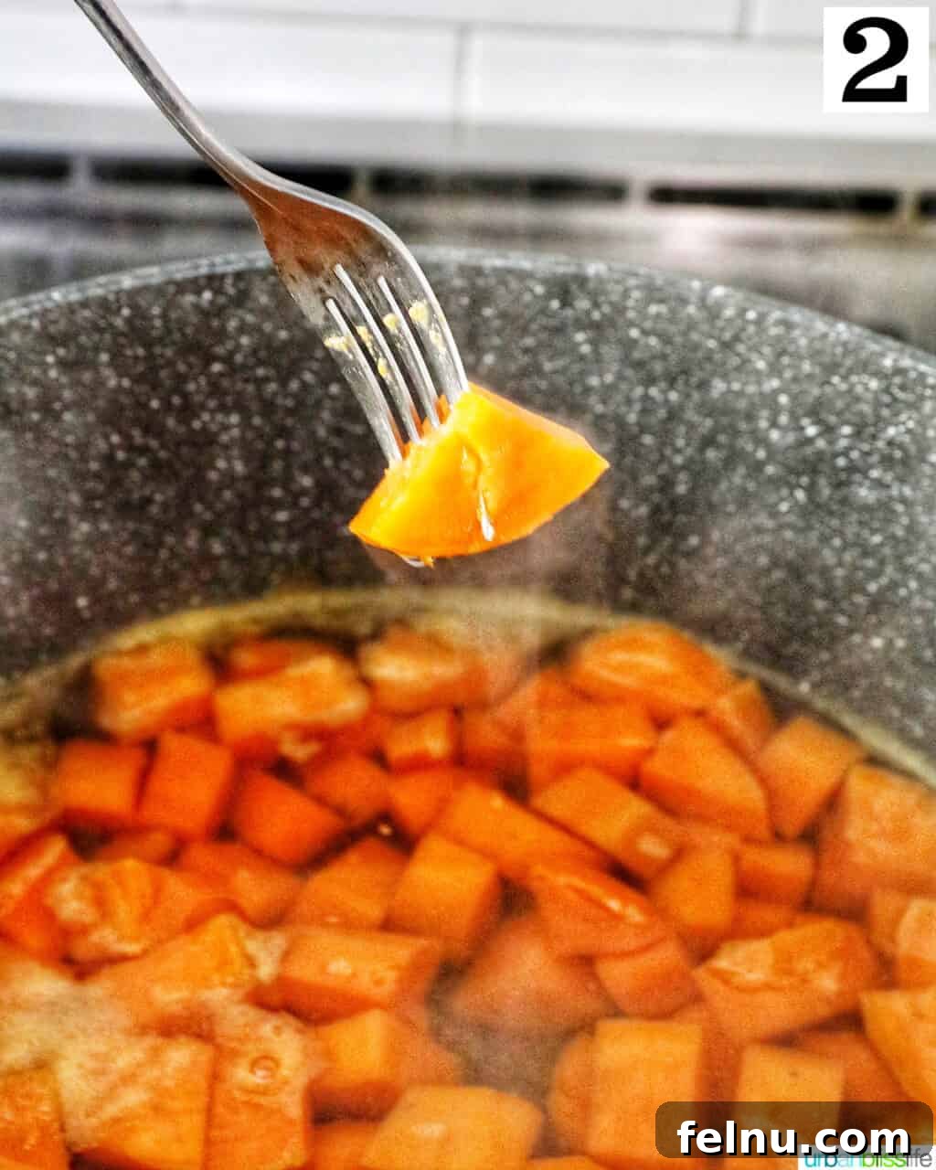 Silky Sweet Potato Puree 6 Fork holding up a piece of sweet potato above a large pot.