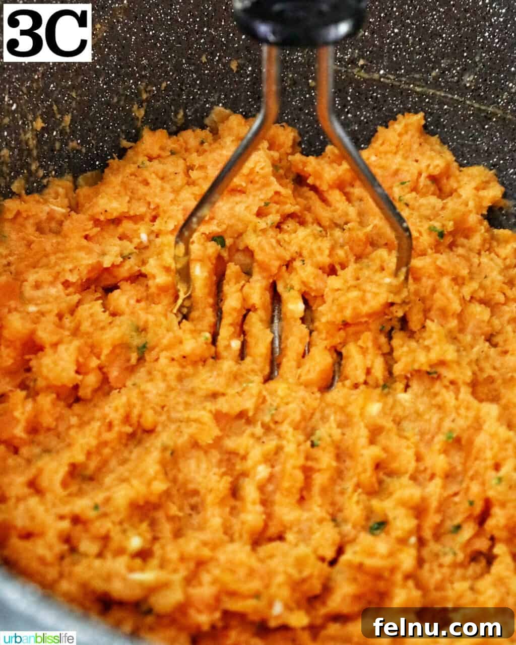 Silky Sweet Potato Puree 9 potato masher mashing up sweet potatoes in a large pot.