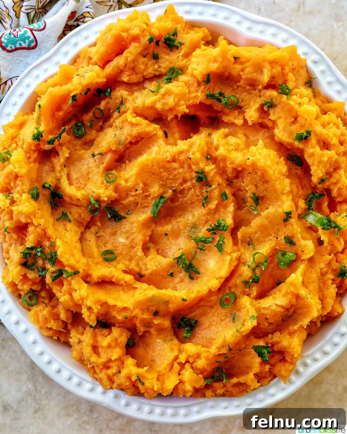 Silky Sweet Potato Puree 10 big white bowl full of mashed sweet potatoes and garnished with fresh herbs.