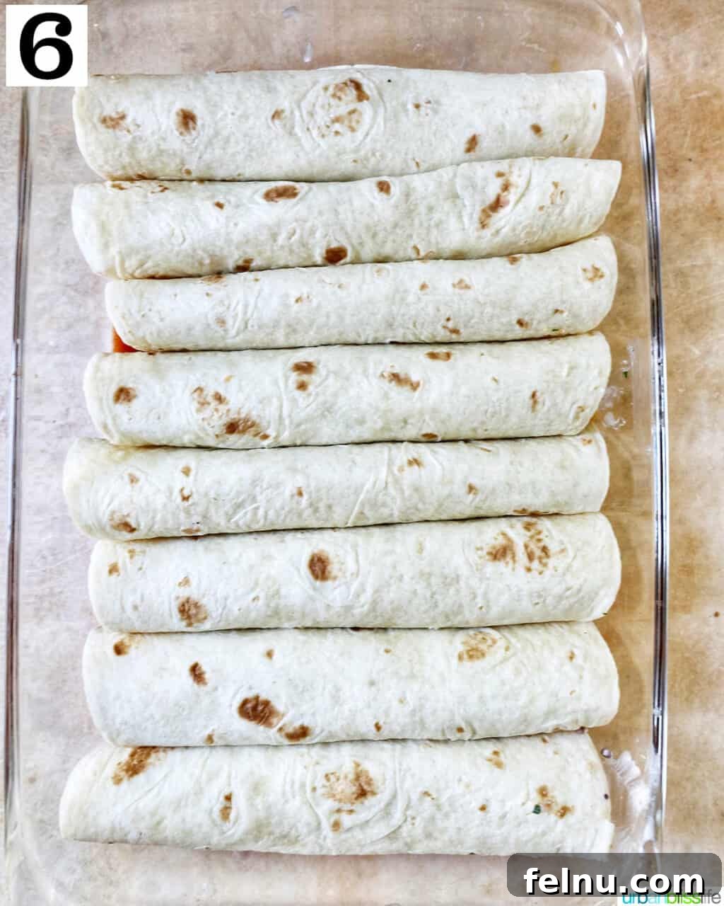 Delicious Leftover Turkey Enchilada Casserole 11 All rolled flour tortilla enchiladas arranged side-by-side in a glass baking dish.