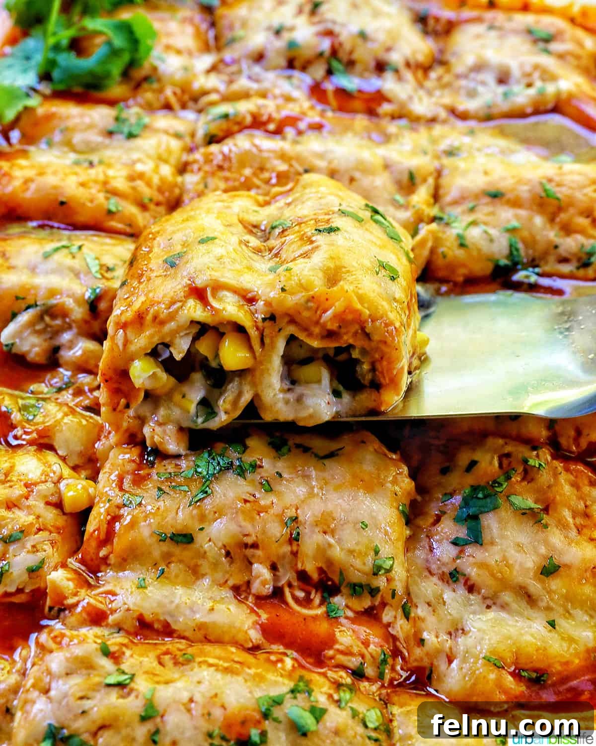 Delicious Leftover Turkey Enchilada Casserole 15 Spatula lifting a square of cheesy turkey enchilada casserole from the baking dish, showing the delicious layers inside.