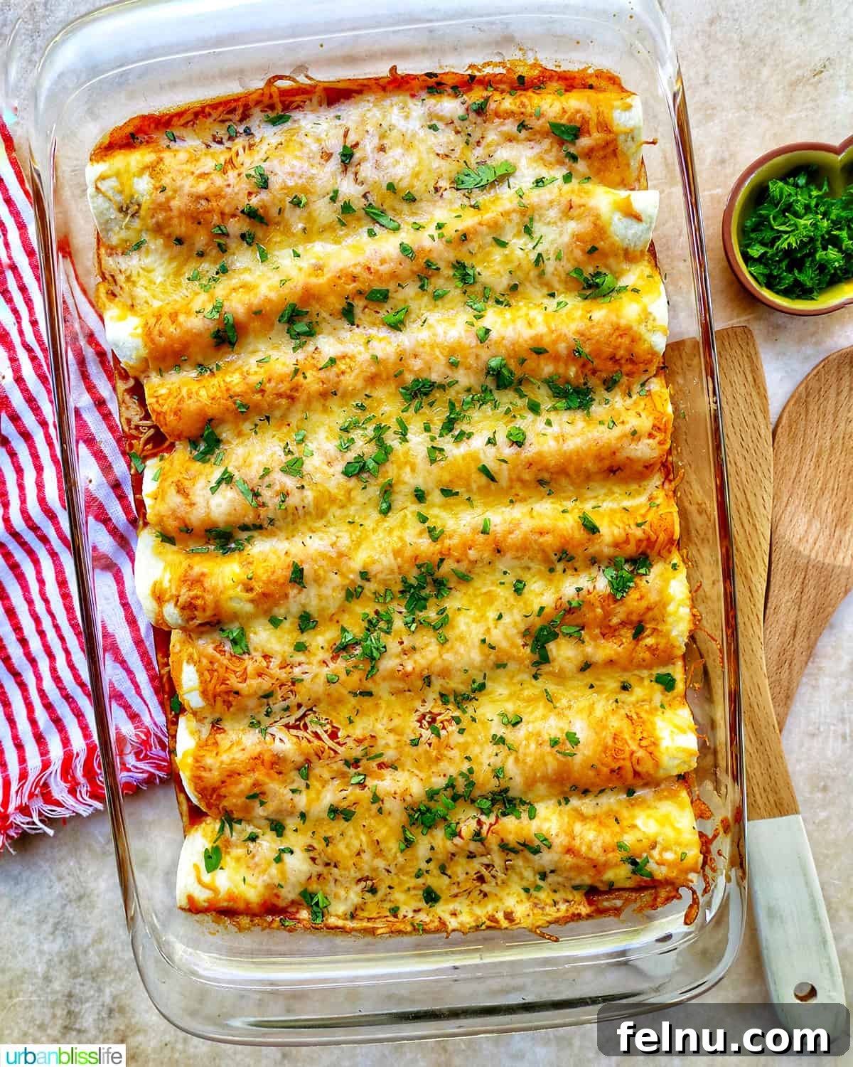 Delicious Leftover Turkey Enchilada Casserole 17 Overhead view of a cheesy turkey enchilada casserole in a glass baking dish with a red and white striped towel, ready to serve.
