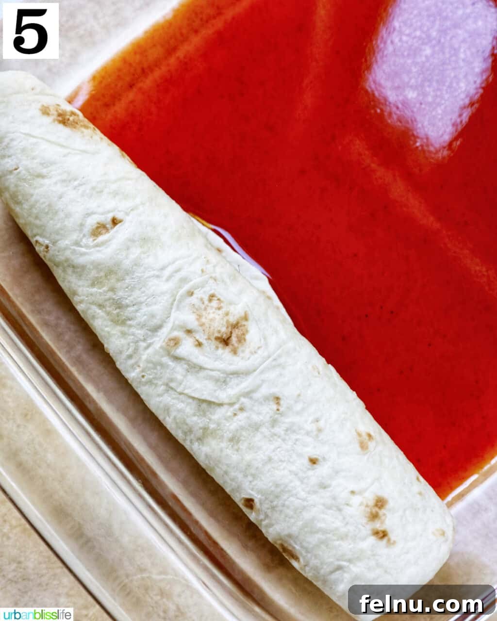 Delicious Leftover Turkey Enchilada Casserole 10 Rolled flour tortilla enchiladas neatly arranged in a glass baking dish, seam-side down.