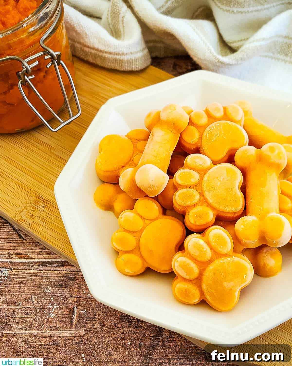 Easy Frozen Pumpkin Pupsicles 2 A plate full of golden frozen pumpkin yogurt dog treats, shaped like paws and bones, ready for a happy pup.