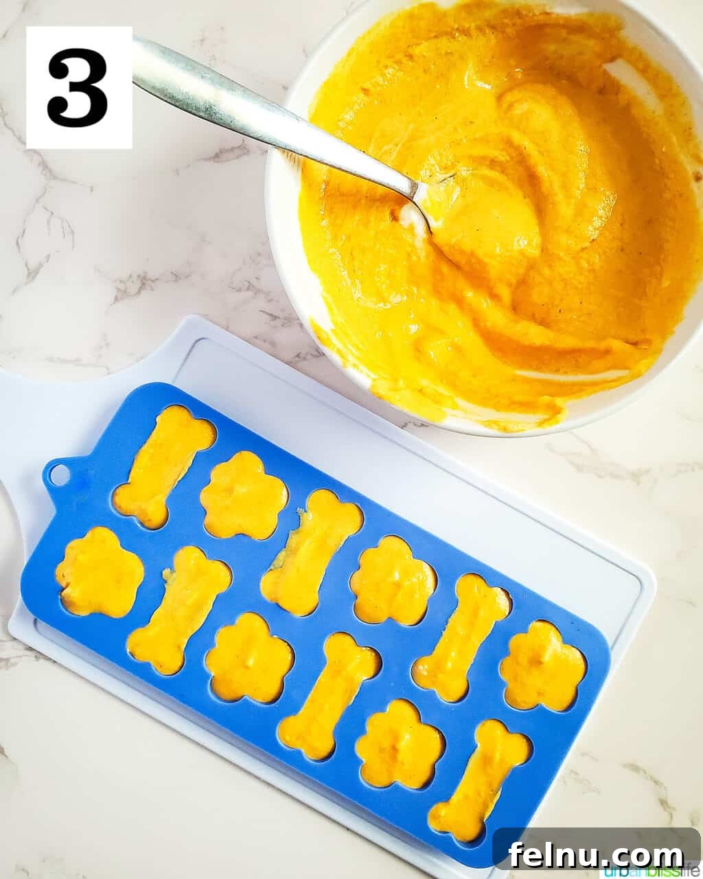 Easy Frozen Pumpkin Pupsicles 7 Silicone dog treat molds, partially filled with the pumpkin yogurt mixture, next to a bowl of remaining batter, showing the filling process.