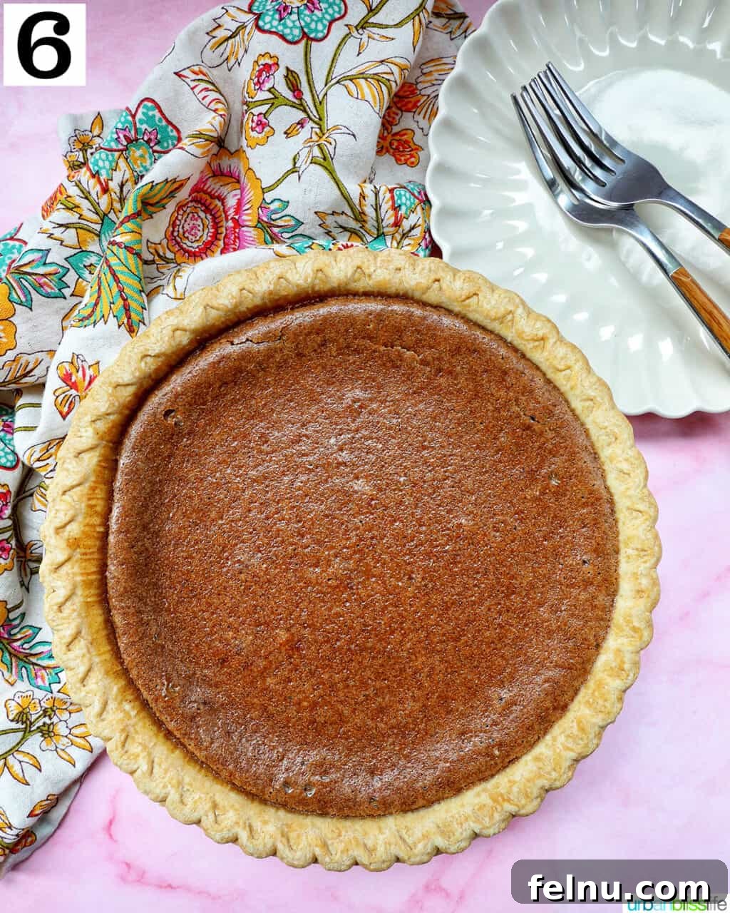 Baked cinnamon pie cooling on a pink table with a colorful napkin and forks.