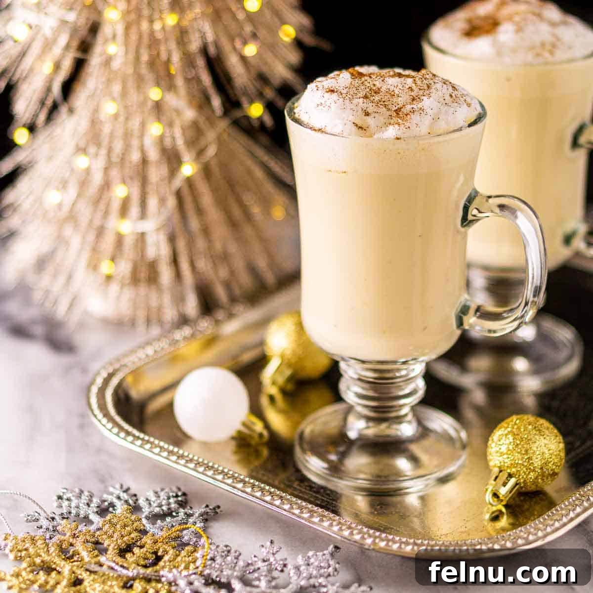 20+ Delicious Baileys Cocktails for Christmas Cheer 2 Glasses of Baileys egg nog beautifully arranged on a serving tray with festive Christmas ornaments, inviting holiday cheer.
