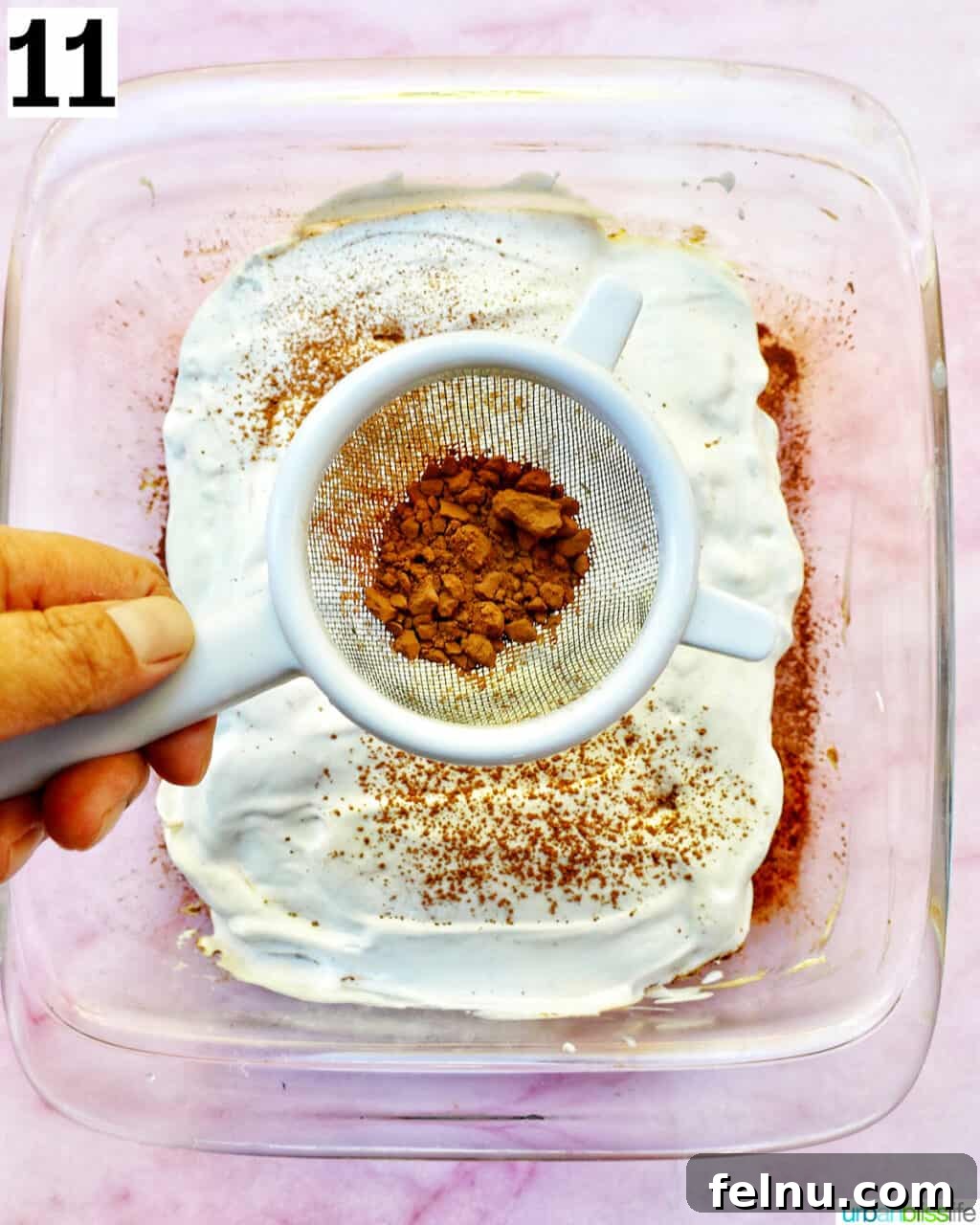 Decadent Dairy-Free Tiramisu 21 The final step: spreading cocoa powder artfully over the top layer of the tiramisu, creating a beautiful finish.