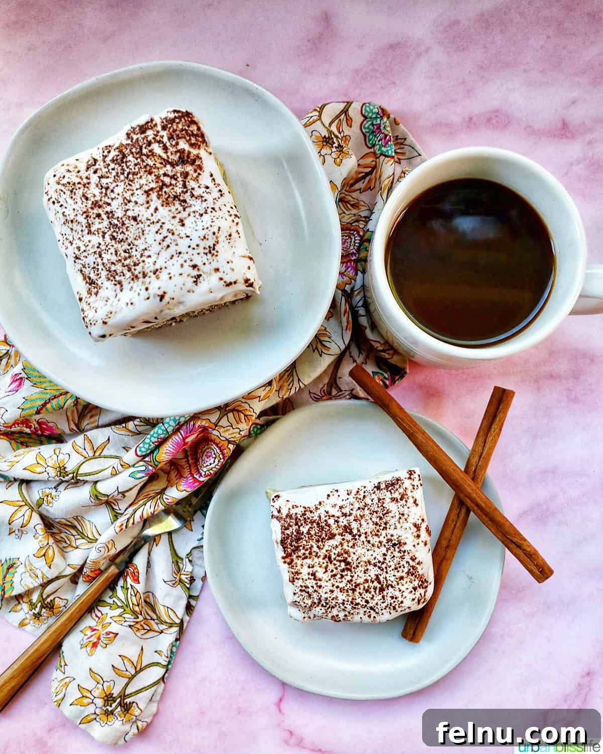 Decadent Dairy-Free Tiramisu 23 Two plates of dairy-free tiramisu dessert, elegantly presented with a cup of coffee, a fork, napkins, and decorative cinnamon sticks.