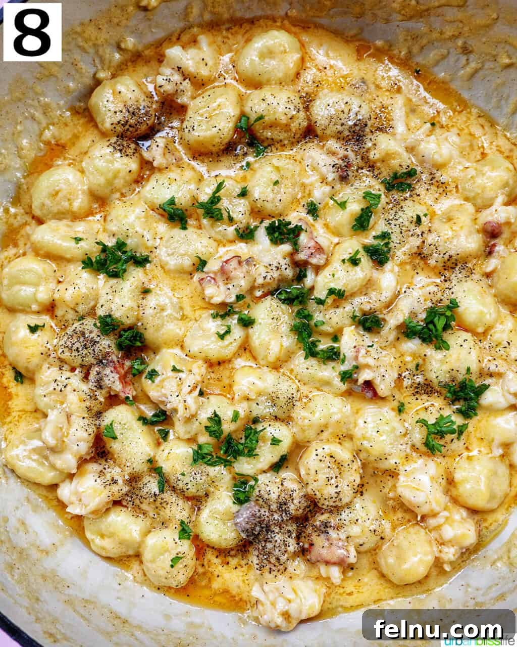 Decadent Lobster Gnocchi 13 Finished creamy lobster gnocchi in a skillet, garnished with fresh herbs.