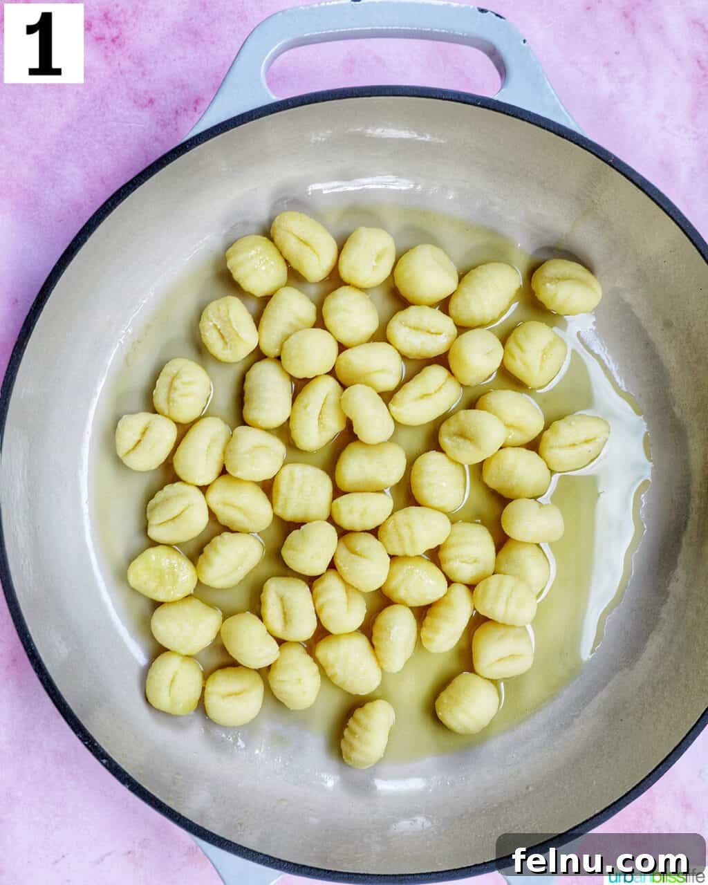Decadent Lobster Gnocchi 5 Gnocchi cooking in a single layer in a large skillet with olive oil.