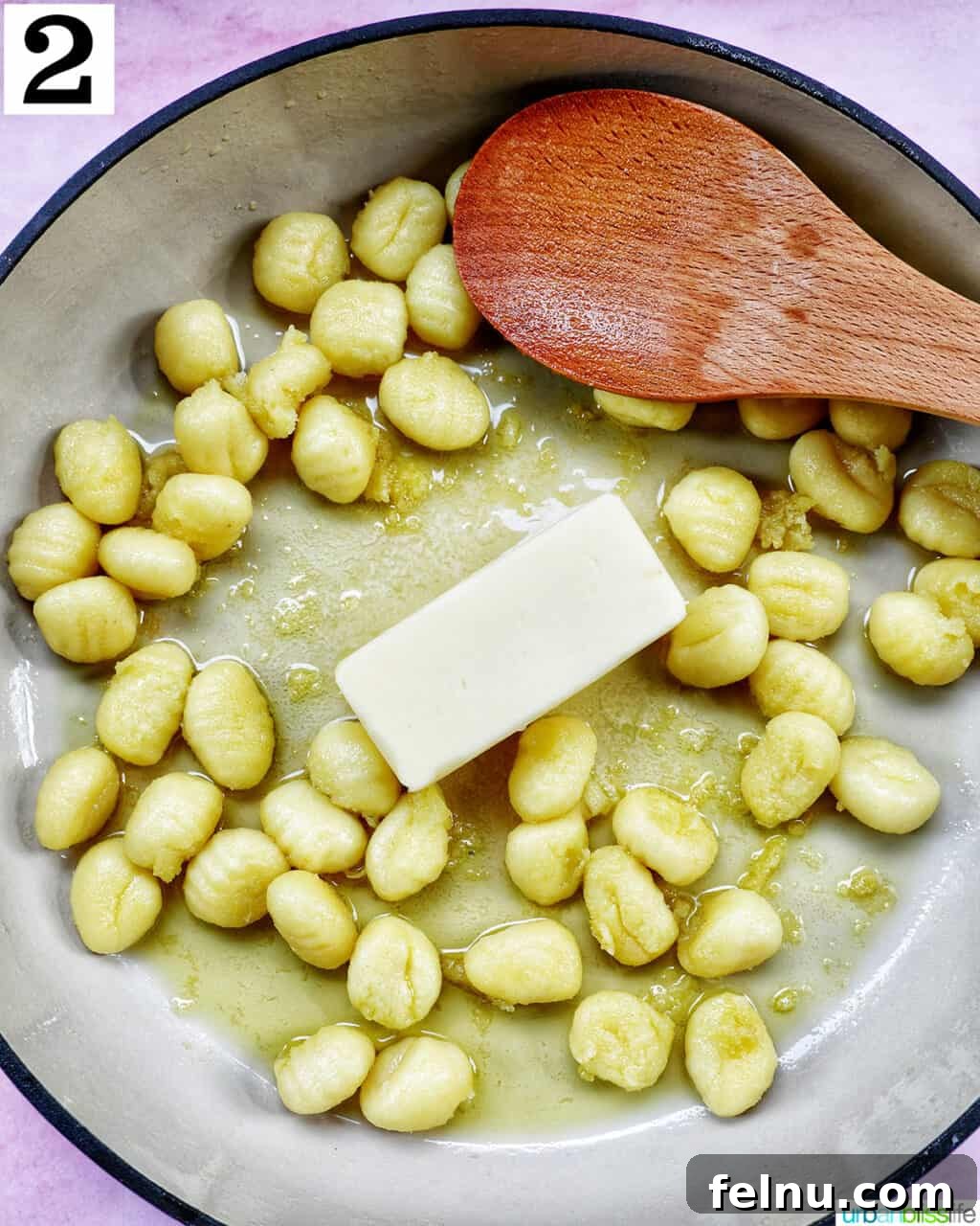 Decadent Lobster Gnocchi 6 Butter being added to gnocchi in a skillet and stirred to combine.