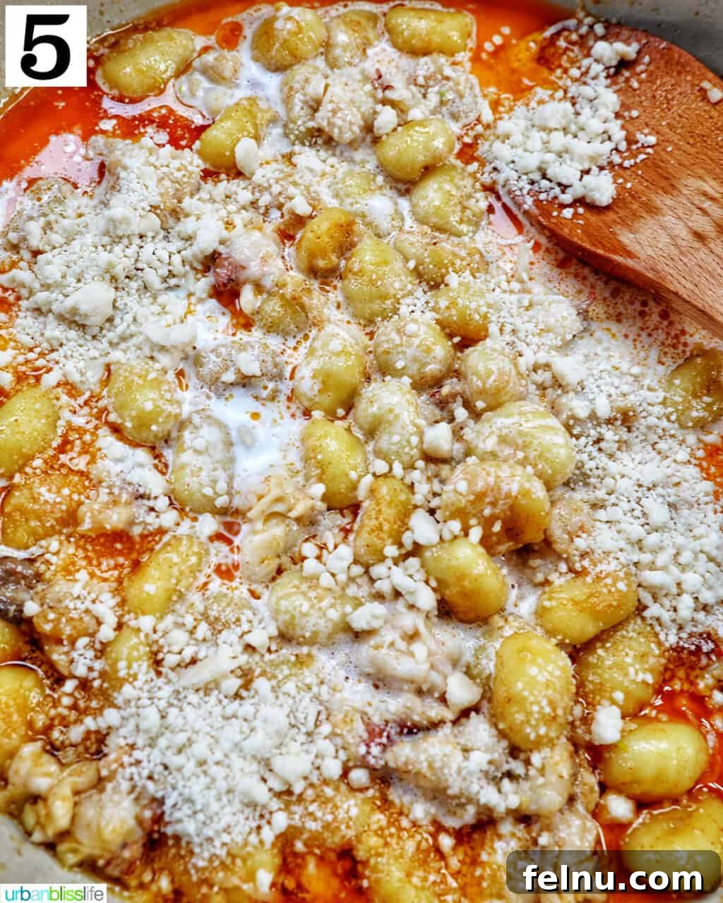 Decadent Lobster Gnocchi 9 Grated Parmesan cheese being sprinkled into the skillet with gnocchi and cream sauce.