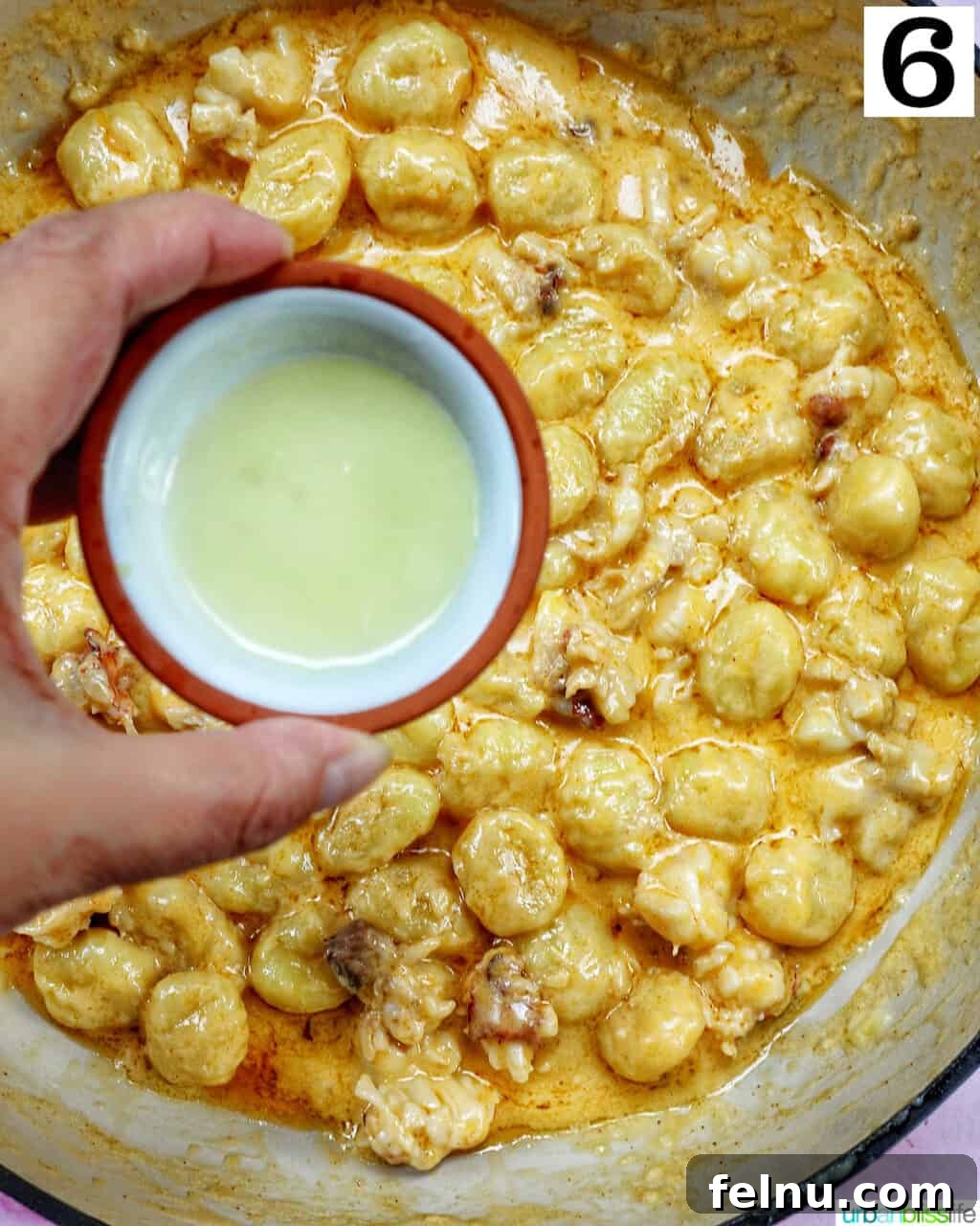Decadent Lobster Gnocchi 10 Lemon juice being drizzled over the creamy lobster gnocchi in the skillet.