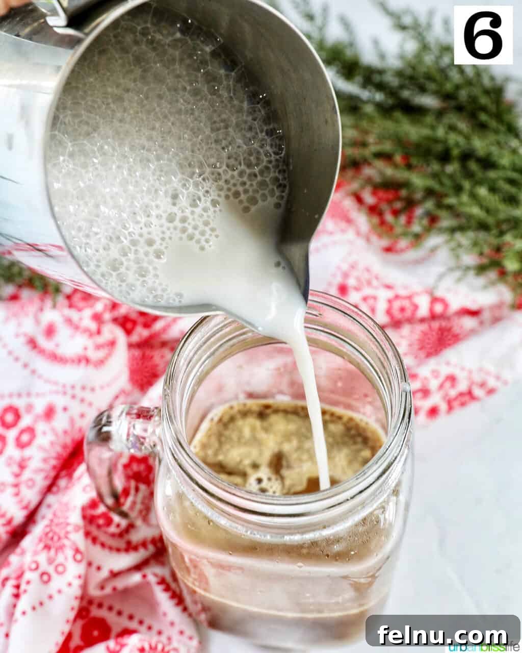 Pouring steamed milk into a mug of white chocolate peppermint mocha