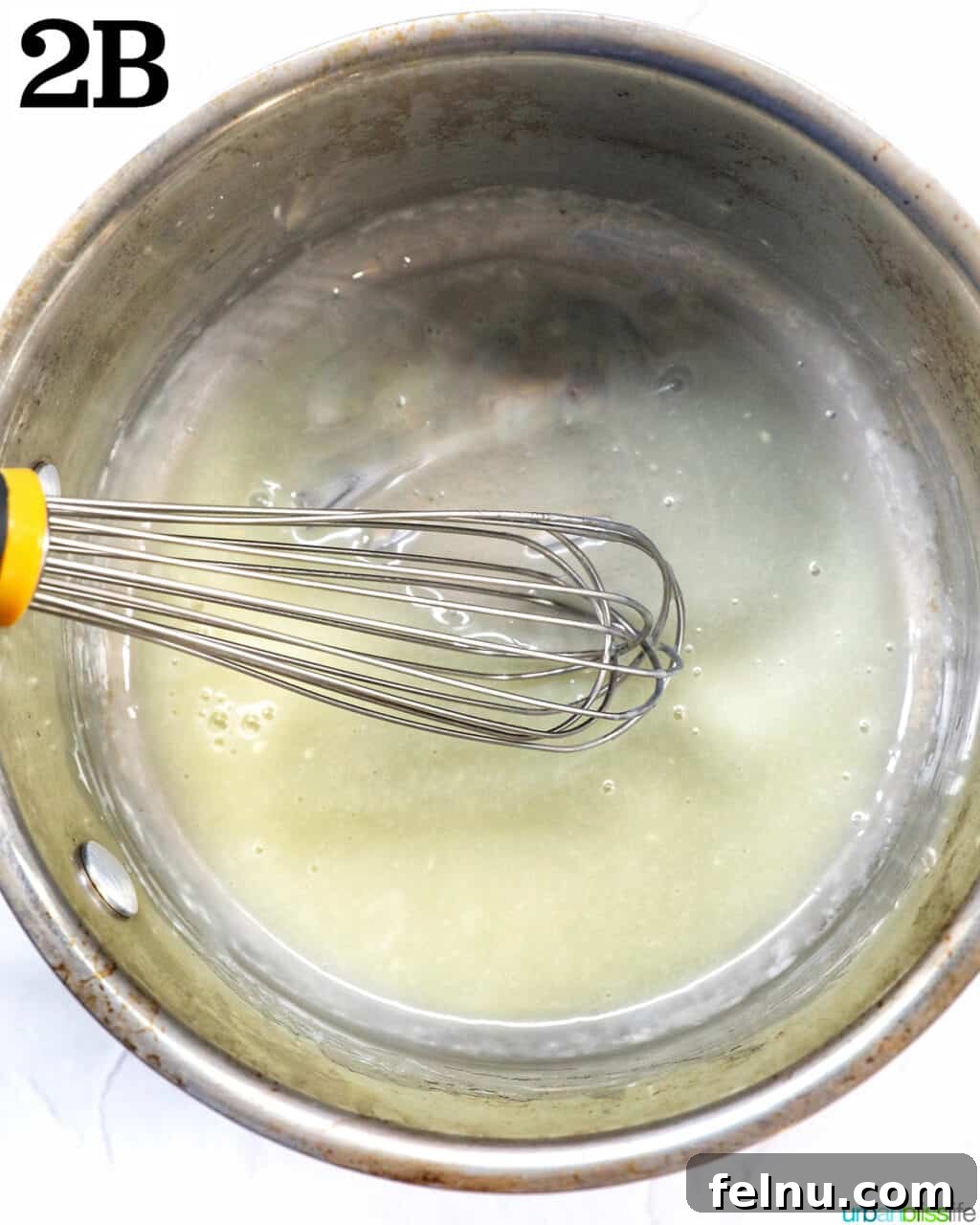 Whisking melted white chocolate and cream in a saucepan