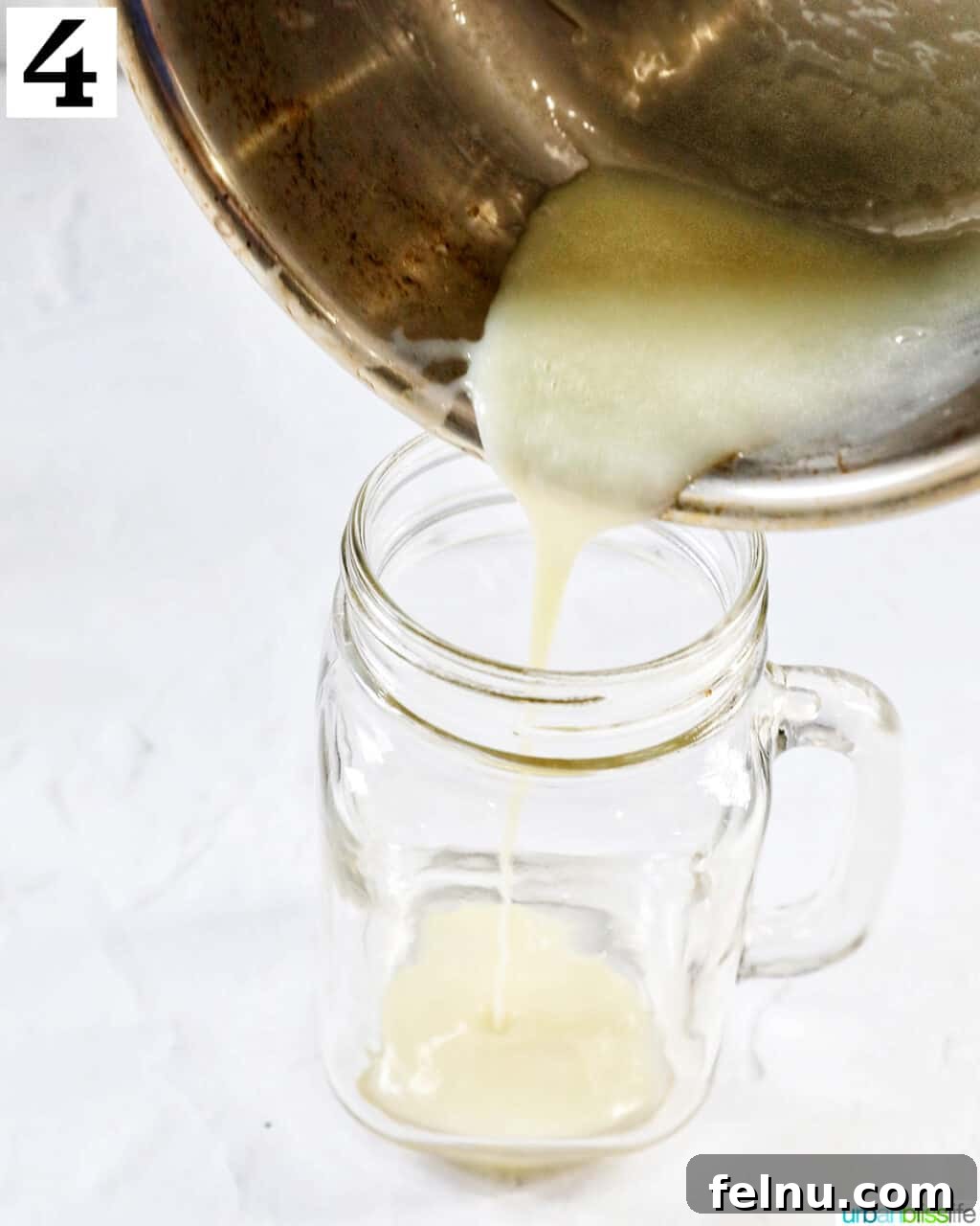Pouring melted white chocolate into a clear glass mug