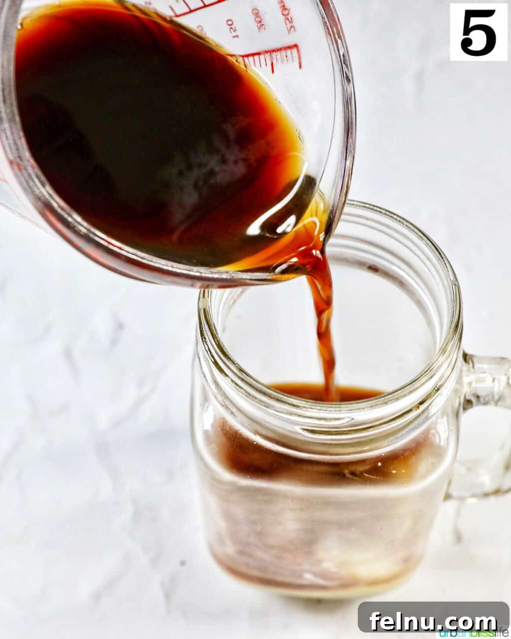 Pouring brewed coffee into a clear glass mug