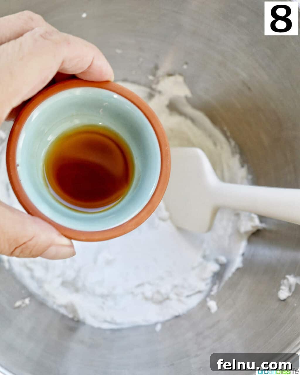 Cool Mint Chocolate Indulgence 12 A hand adding a spoonful of vanilla extract over freshly whipped cream, preparing it for the chocolate peppermint pie filling.