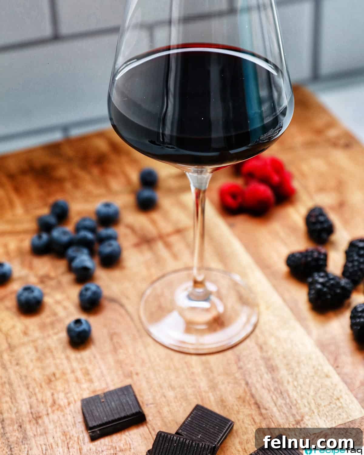 Cool Mint Chocolate Indulgence 20 A glass of rich Zinfandel red wine sits on a rustic wooden board, surrounded by fresh fruits and various chocolates, suggesting a perfect pairing.