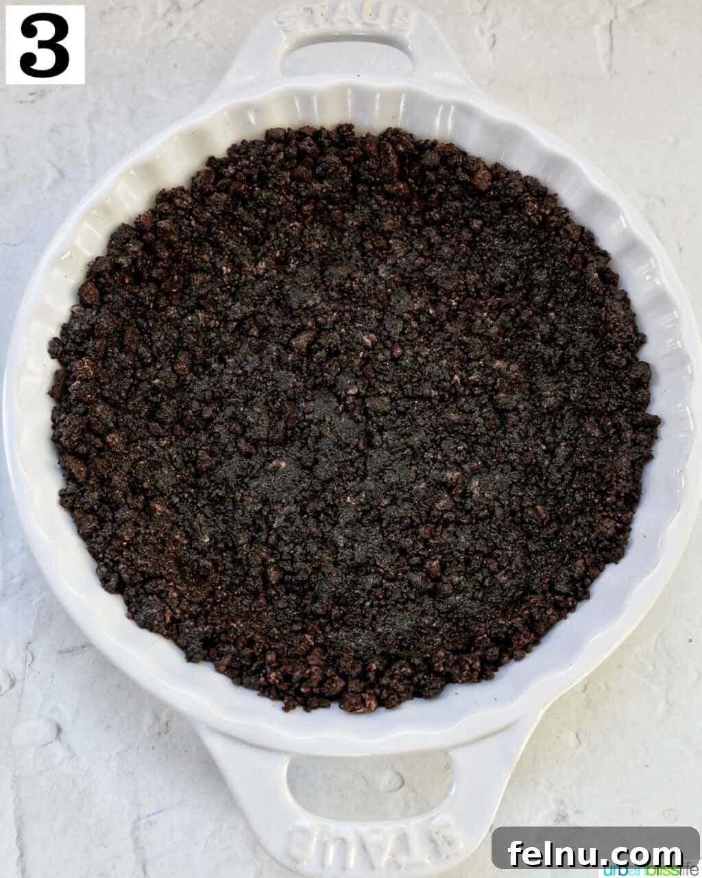 Cool Mint Chocolate Indulgence 7 A perfectly pressed crushed Oreo crust, golden brown from baking, set neatly in a white pie plate, ready for filling.