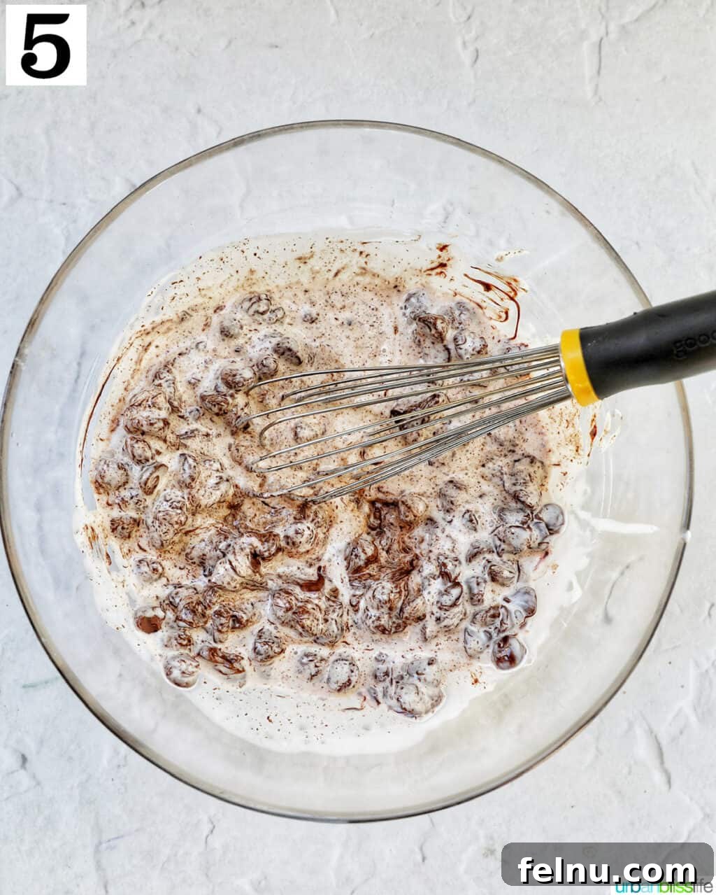 Cool Mint Chocolate Indulgence 9 A whisk stirring warm heavy cream and melting chocolate chips in a glass bowl, creating a smooth ganache for the pie filling.