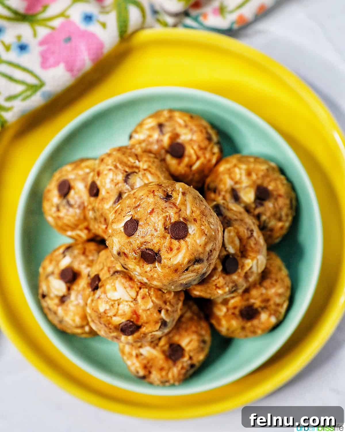 Chewy Peanut Butter Chocolate Chip Oat Bites 3 An overhead view of a stack of Peanut Butter Chocolate Chip Oatmeal Balls, showcasing their inviting texture on a vibrant green and yellow plate.