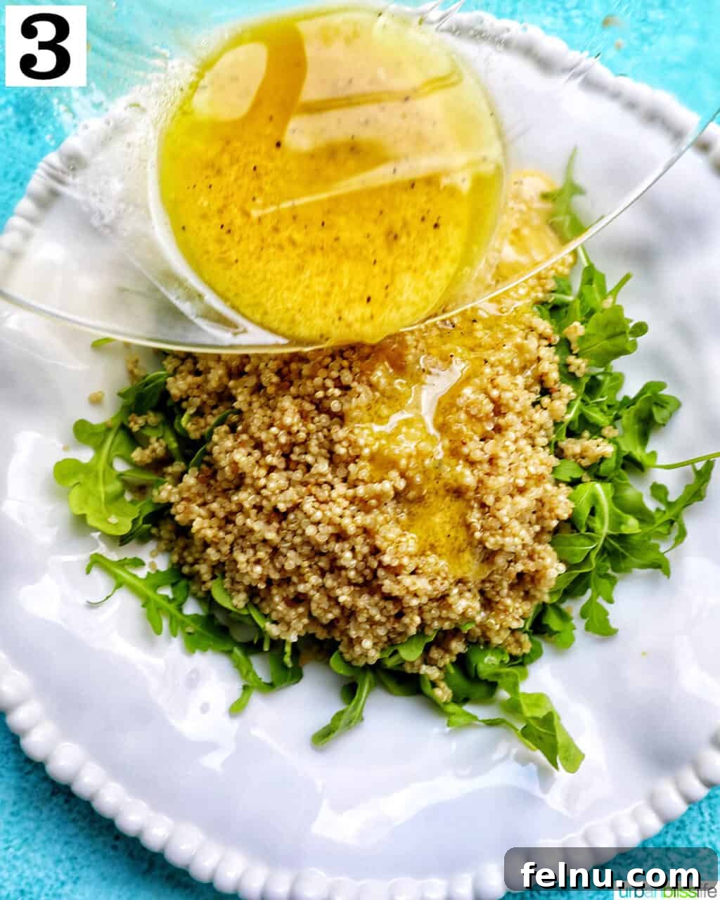 Vibrant Arugula Quinoa Harvest 8 pouring salad dressing over a white bowl with arugula and quinoa salad.