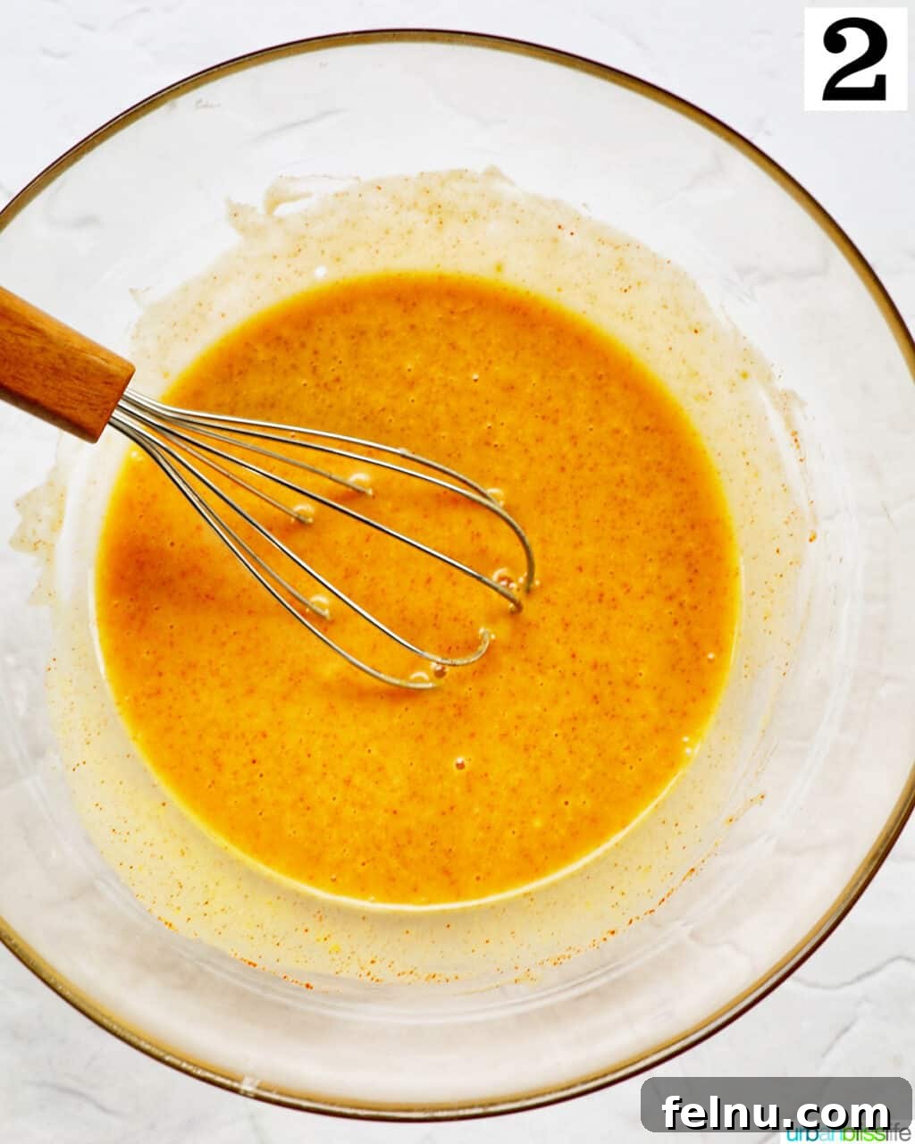 whisk stirring honey mustard sauce in a glass bowl.