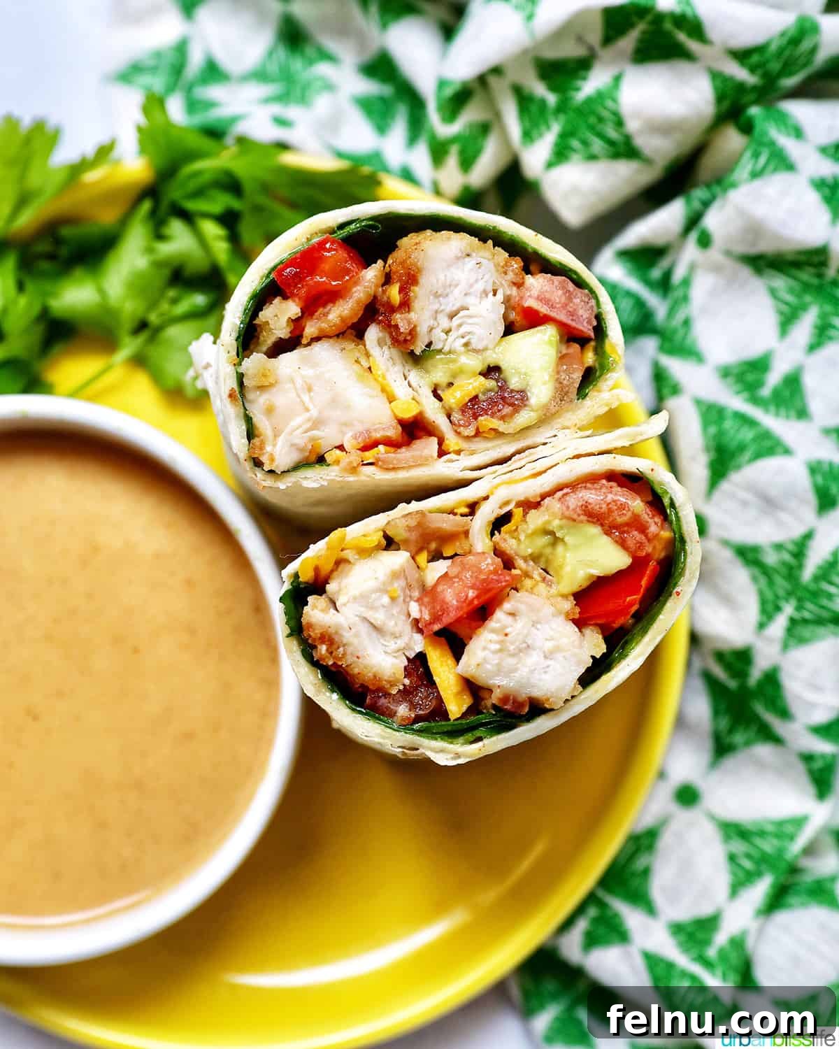 honey mustard chicken wrap cut in half next to a bowl of honey mustard dipping sauce.