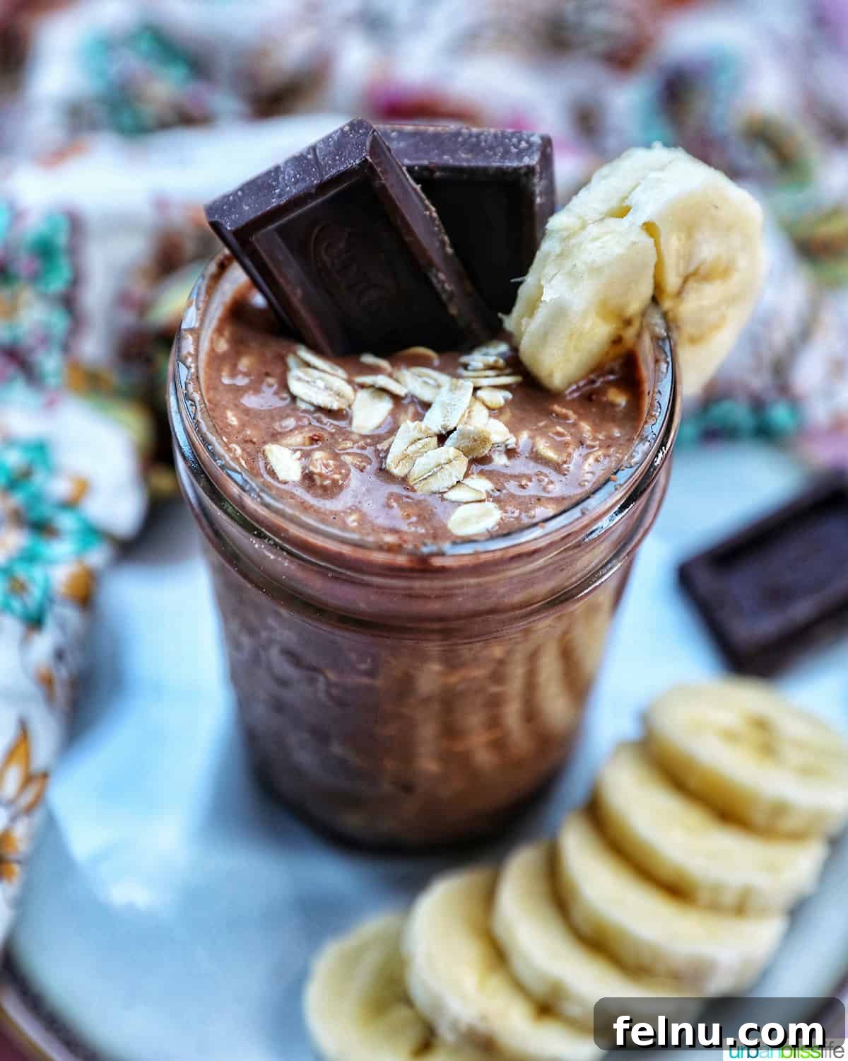 Chocolate Protein Power Oats 2 Chocolate protein overnight oats topped with banana slices and chocolate pieces.