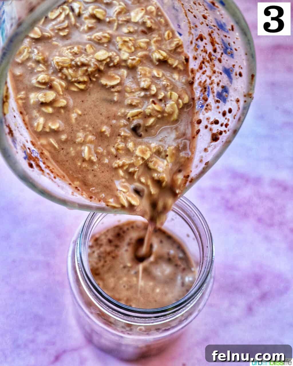 Pouring chocolate protein overnight oats from a large glass bowl into a mason jar.
