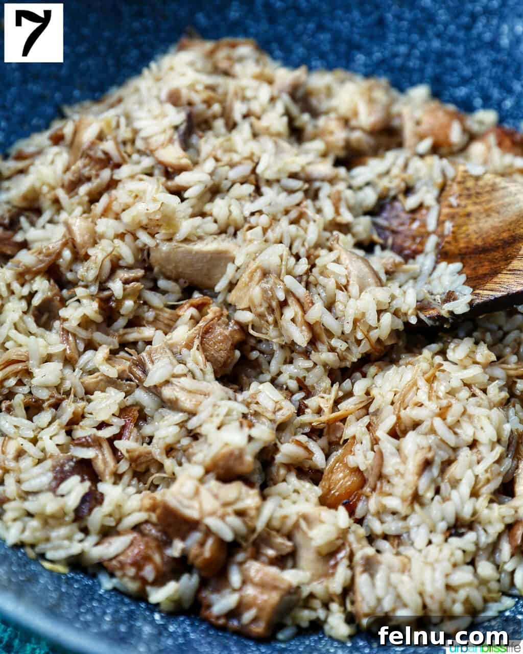 Savory Garlic Adobo Fried Rice 11 Adobo fried rice being stirred in a wok with a wooden spoon, ensuring all ingredients are well combined.