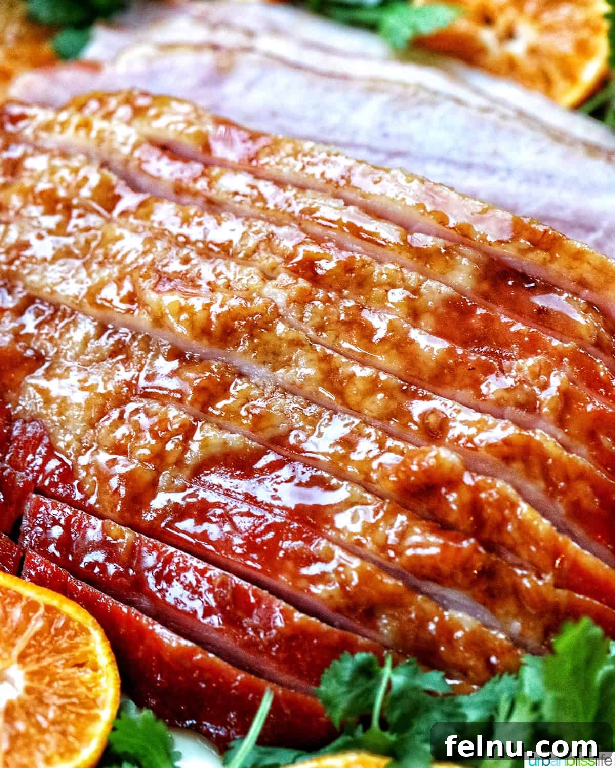Air Fryer Ham Orijinal Başlık: Crispy & Quick: Air Fryer Ham Recipe 13 Sliced honey glazed air fryer ham on a plate with fresh herbs and sliced oranges