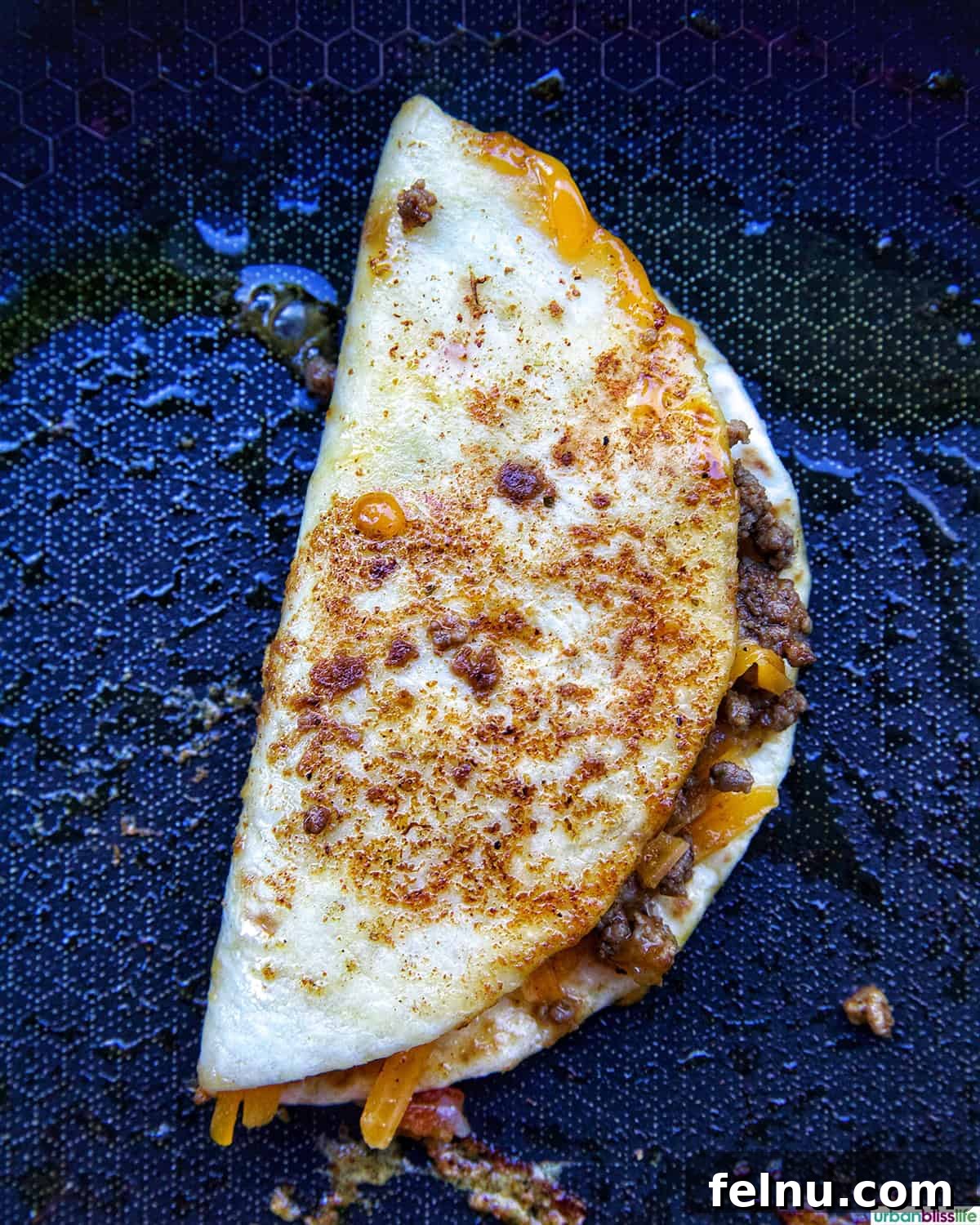 Golden-Crisp Beef Tacos 14 A folded crispy beef taco cooking in a hot skillet, achieving a golden-brown and crispy texture.