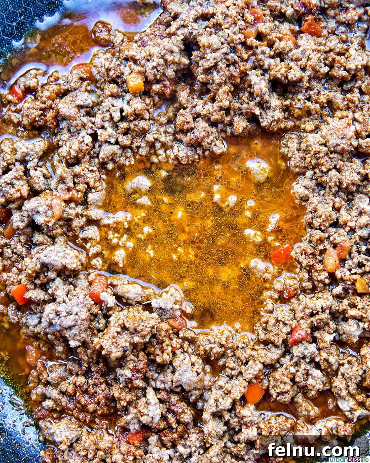 Golden-Crisp Beef Tacos 9 Beef broth being poured into the seasoned ground beef mixture in a pan.