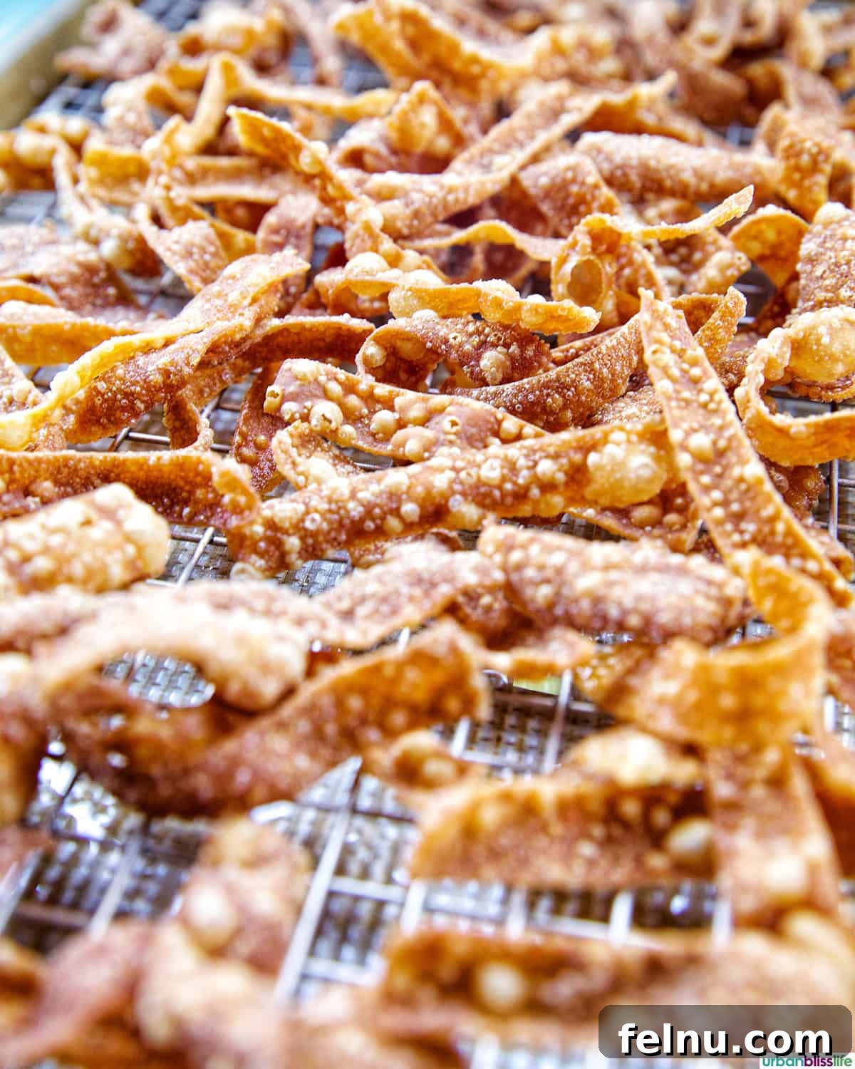 Freshly fried wonton strips cooling on a wire rack to maintain crispness.