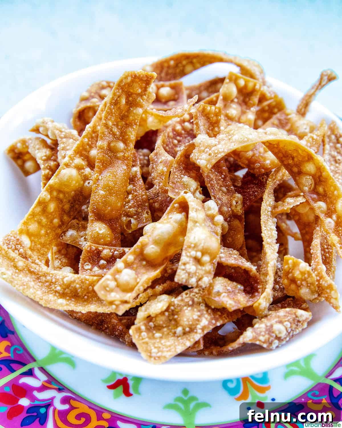 A visually appealing bowl overflowing with perfectly golden and crispy Fried Wonton Strips, ready for snacking or topping.