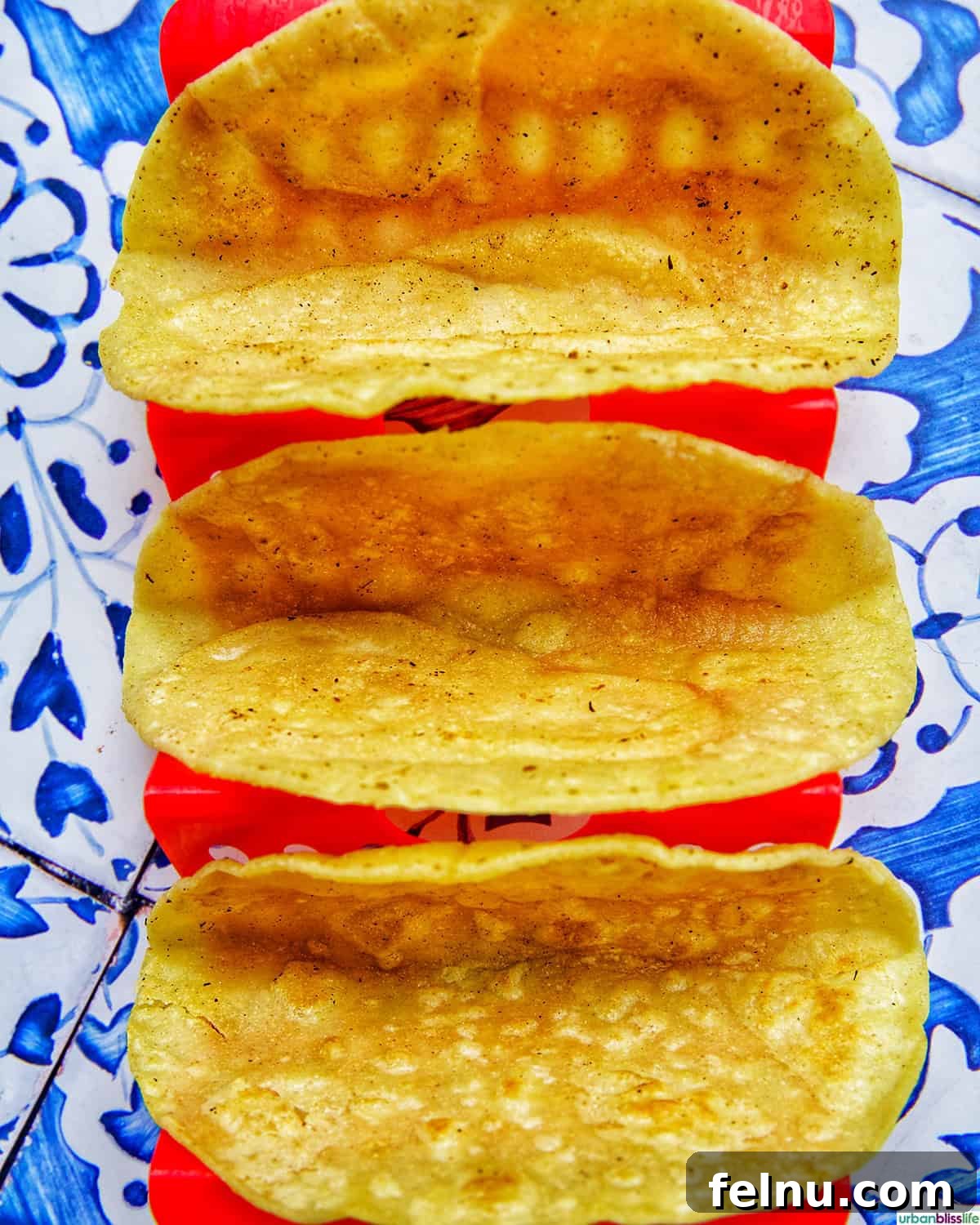 Three empty taco shells nestled in a taco holder, ready for filling.