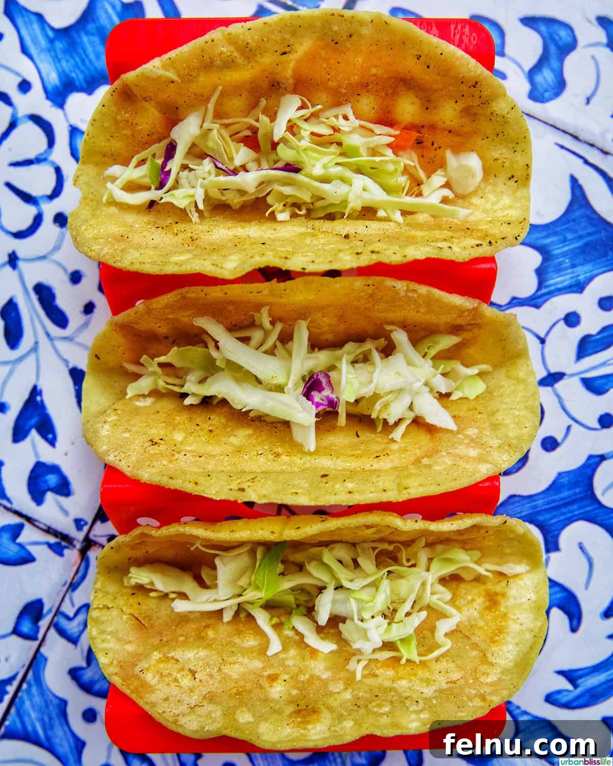 Three taco shells partially filled with a generous base layer of shredded cabbage slaw.