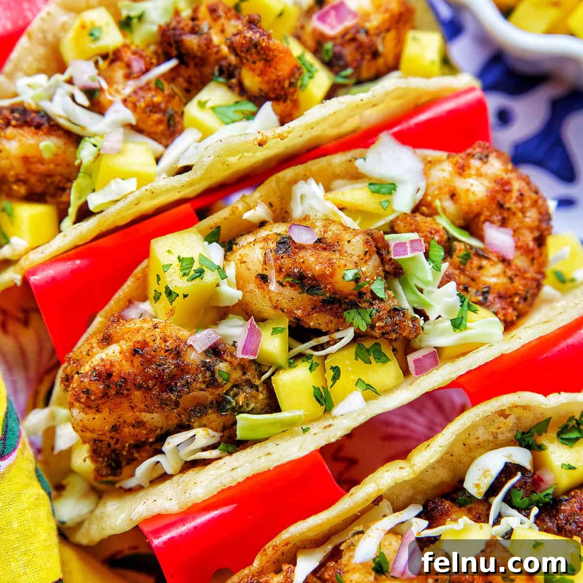 Three air fryer shrimp tacos in a red taco stand, ready for serving.