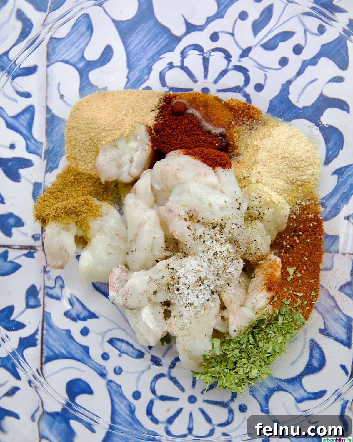 Fresh shrimp seasoned with a vibrant blend of spices in a mixing bowl.
